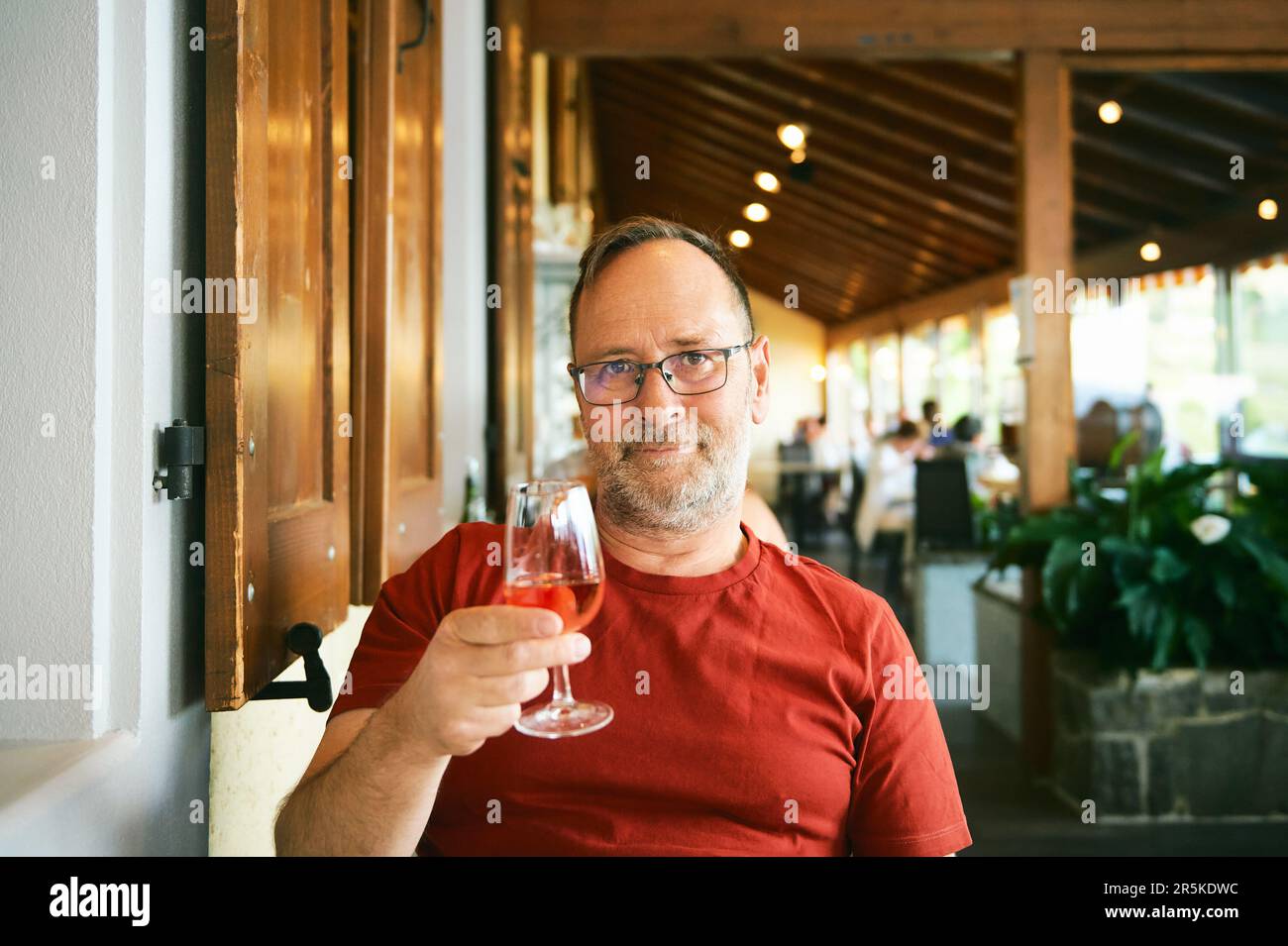 Portrait of middle age man in indoor restaurant, holding glass of wine Stock Photo