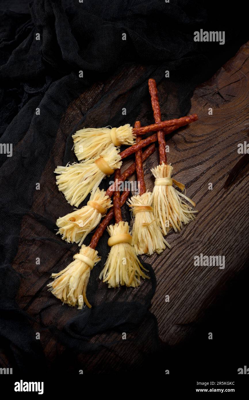 Witches Broom of smoked cheese suluguni and salami. Original idea Halloween snack. Stock Photo