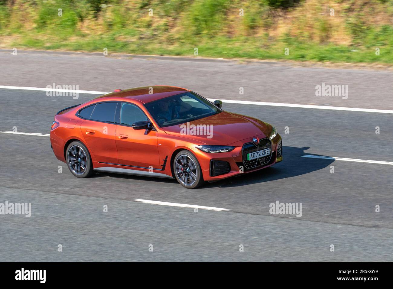 2022 Orange BMW I4 M50,  544 Xdrive Electric 83.9Kwh Auto Orange Car Hatchback Electricity 400 kW travelling on the M61 motorway, UK Stock Photo