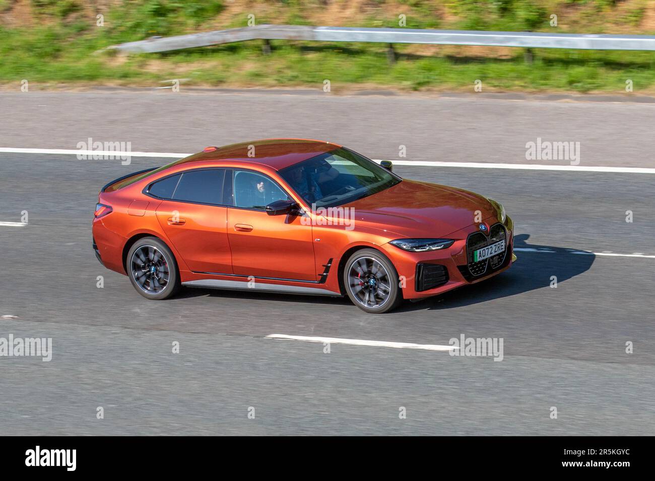 2022 Orange BMW I4 M50,  544 Xdrive Electric 83.9Kwh Auto Orange Car Hatchback Electricity 400 kW travelling on the M61 motorway, UK Stock Photo