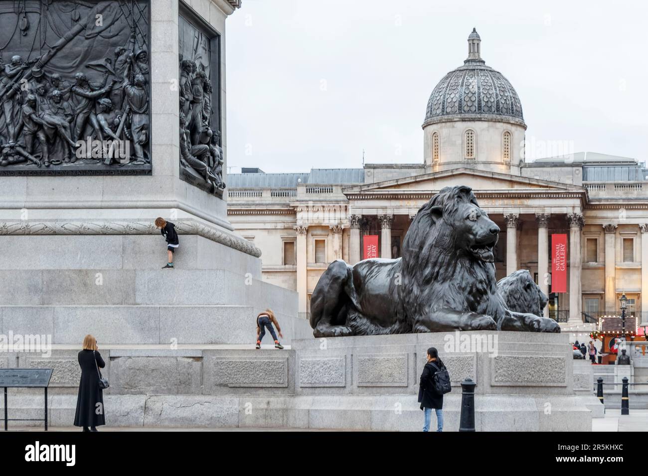 Children climb and play on the plinth of Nelson's Column in Trafalgar Square, London, UK Stock Photo