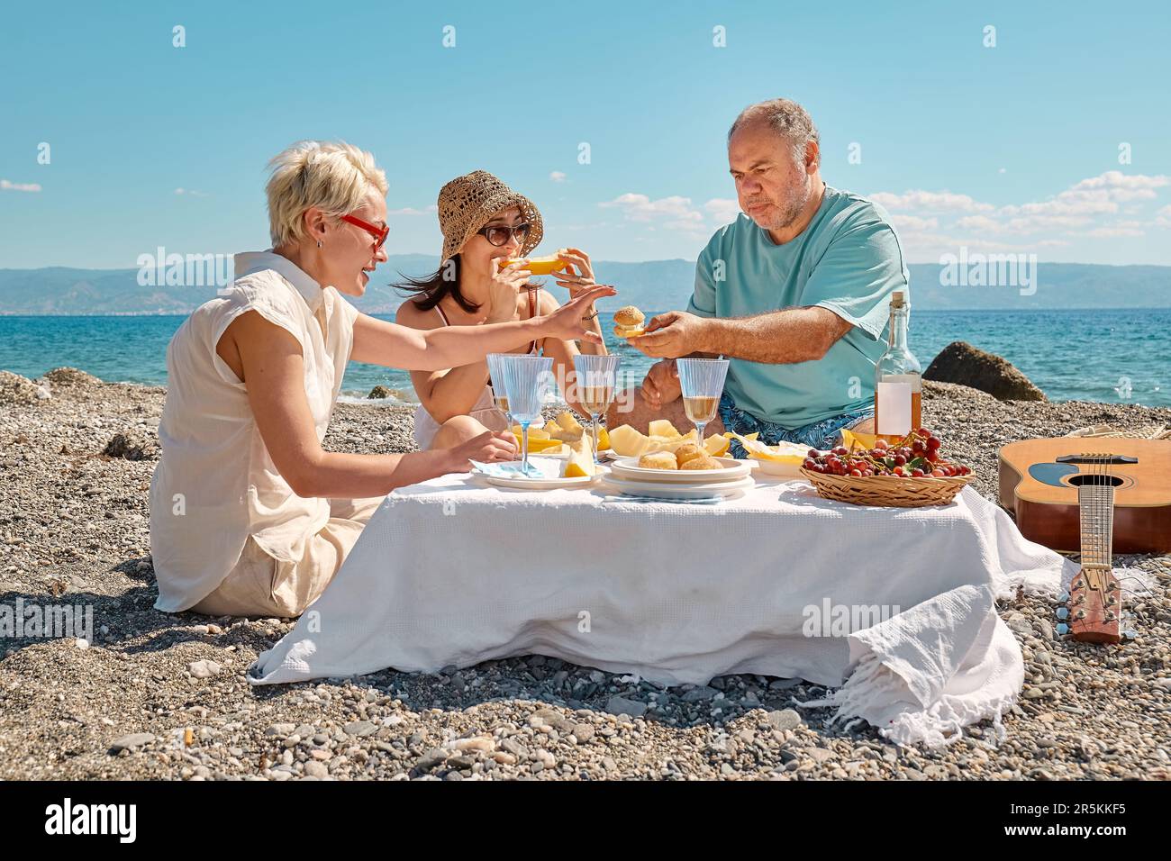 Summer beach picnic. Group of middle aged friends having picnic with