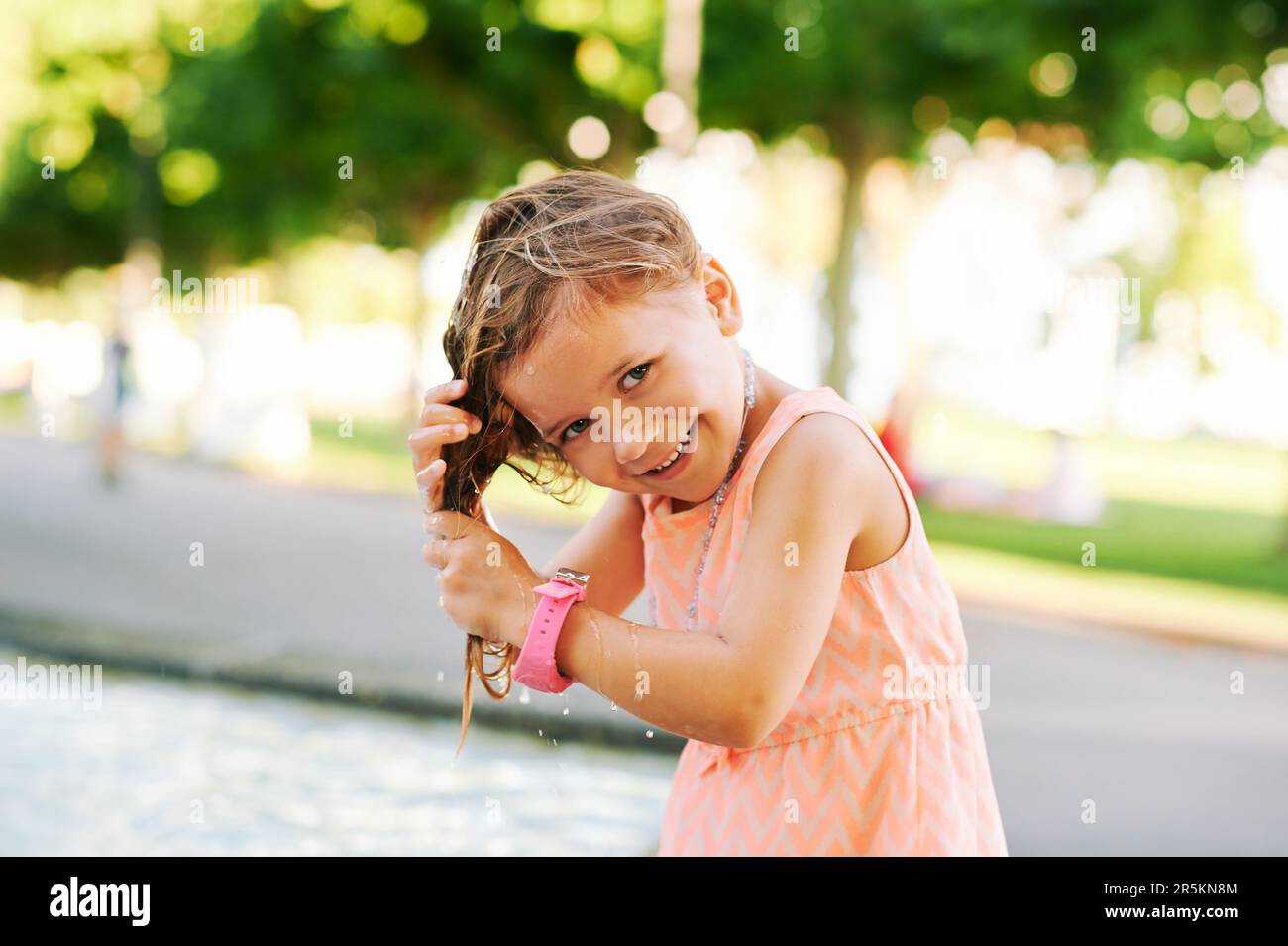 wetting little Funny little girl wetting hair in fountain, hot summer day, child playing  outside Stock Photo - Alamy