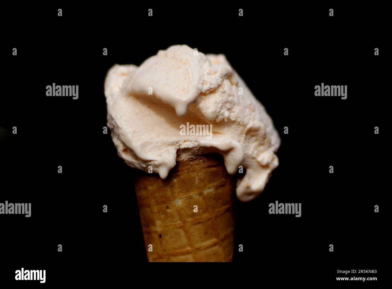 Orange flavored ice cream in a waffle cone on a black background - Italian gelato Stock Photo