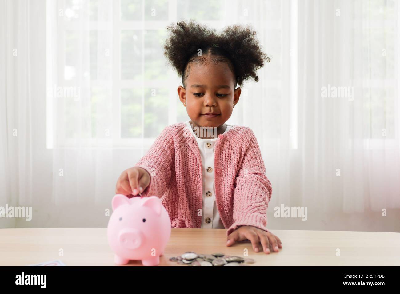 Little girl putting coin of cash into ceramic piggy bank Stock Photo ...