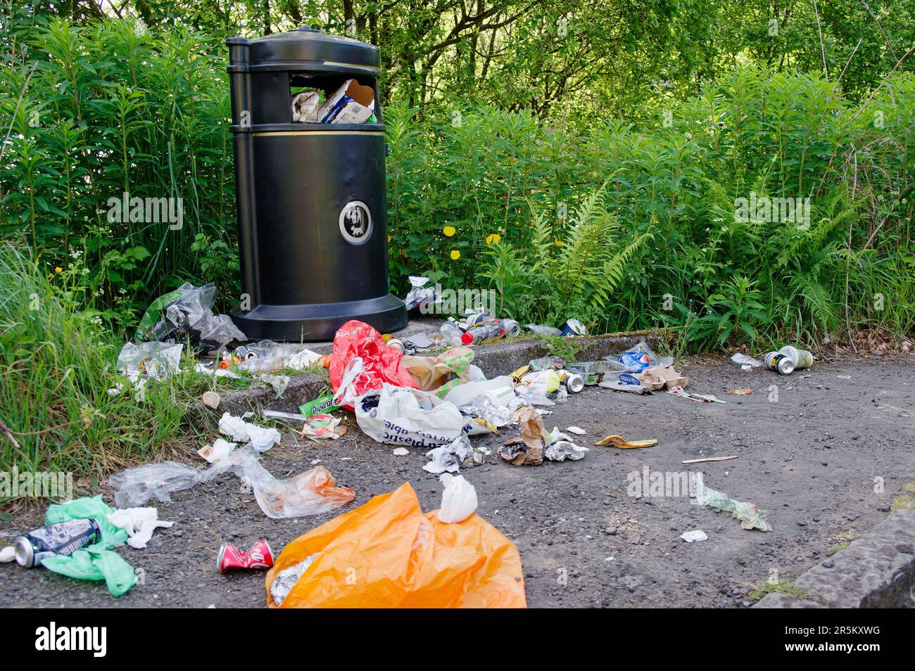 Rubbish bin at national park area overflowing with empty food bags and