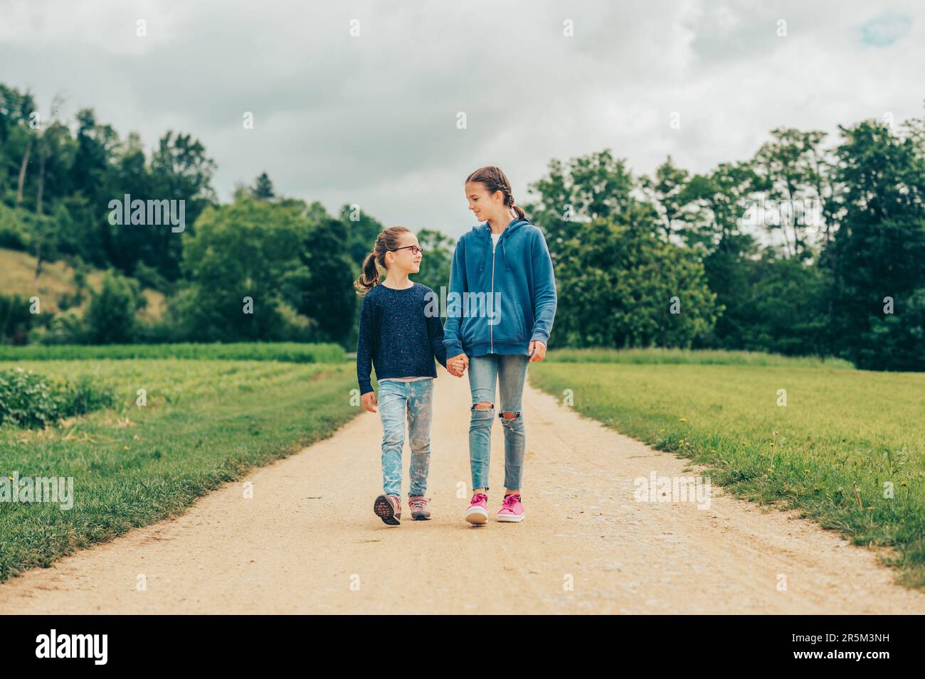 Two little girls walking in fields, happy childhood in countryside, kids spending time in the nature Stock Photo