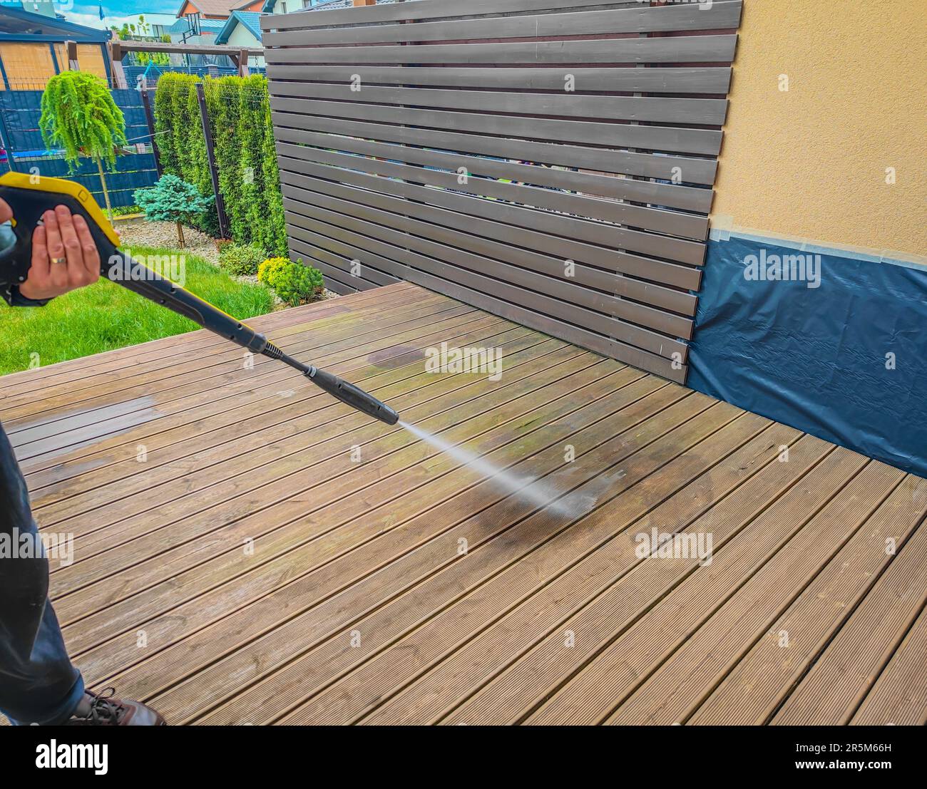 Man cleaning wooden terrace decking before oiling and painting with a