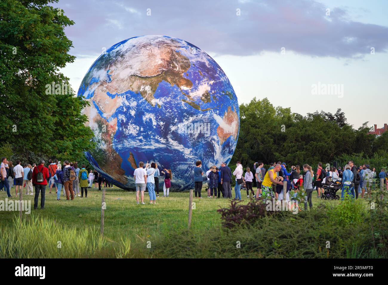 Brno, Czechia - July 12, 2020: People walking in front of inflatable Earth model placed on green grass meadow near planetarium park Stock Photo