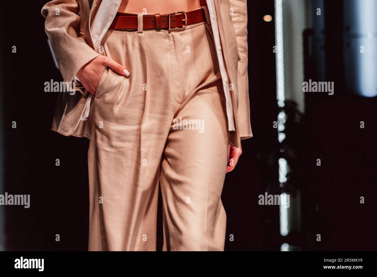 Fancy details of stylish neutral beige outfit, classy jacket, pants with leather brown belt. Cloth unisex concept Stock Photo