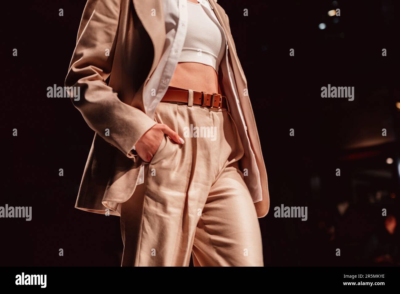Fancy details of stylish neutral beige outfit, classy jacket, pants with leather brown belt. Cloth unisex concept Stock Photo