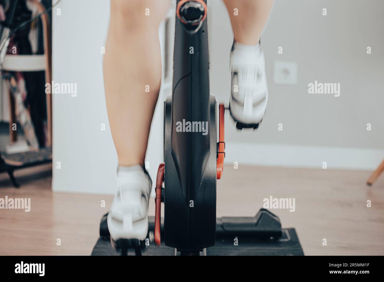 Women leg with white cycling boots cycling on a spinning gym bike indoor scene with motion fast blur Stock Photo