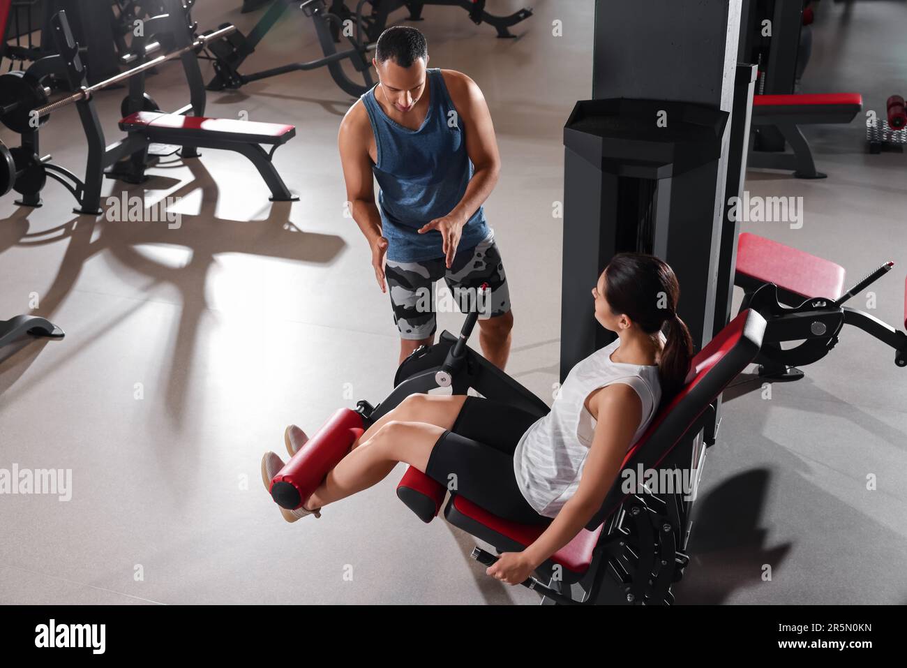 Trainer explaining woman how to do exercise properly in modern gym Stock Photo Alamy
