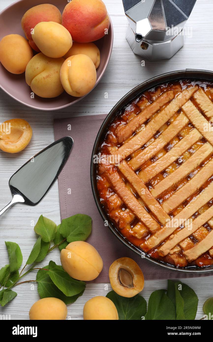 Delicious apricot pie in baking dish and fresh fruits on white wooden table, flat lay Stock Photo
