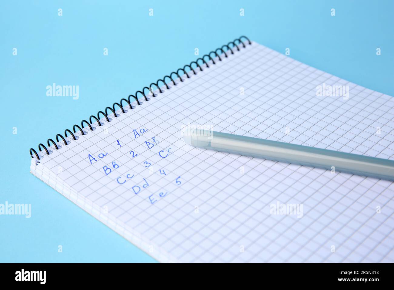 Letters and numbers written in notepad with erasable pen on light blue ...