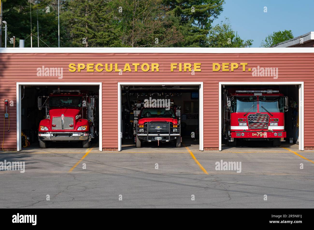 Three emergency fire trucks parked inside the Speculator, NY USA Fire Dept. building with the garage doors open for training. Stock Photo