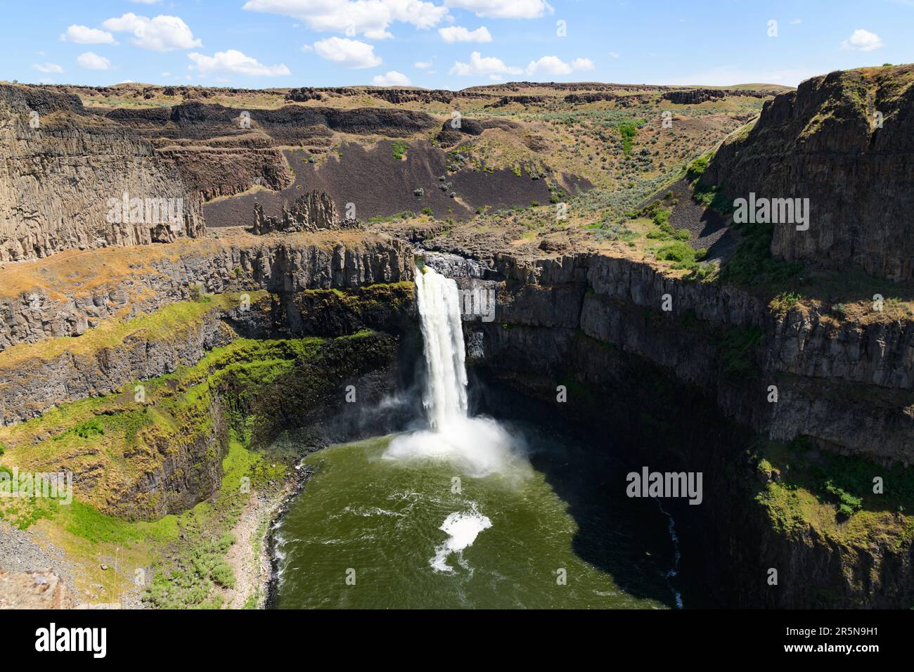 Palouse Falls dropping into pool in Eastern Washington State in sunshine surrounded by basalt rock Stock Photo