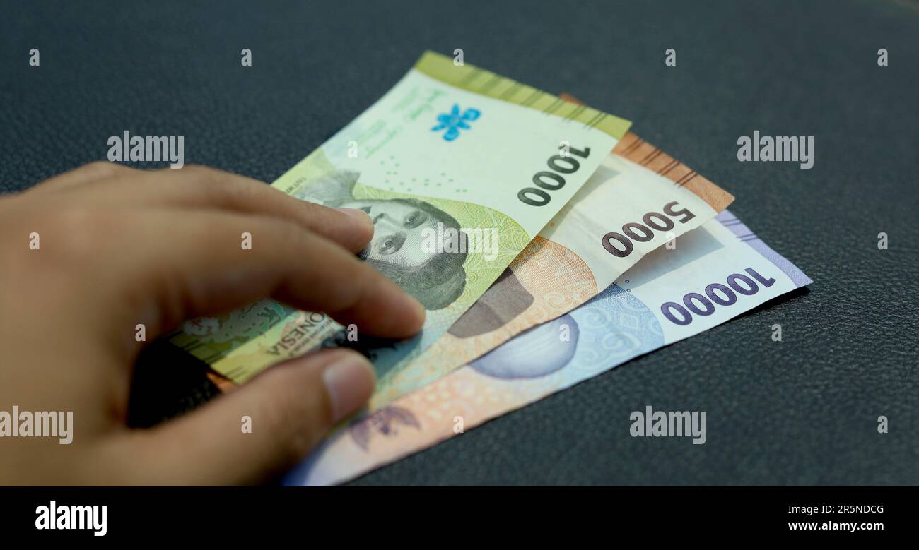 Indonesian man hand holding rupiah money. Indonesian currency. cash in hand concept and close up view Stock Photo