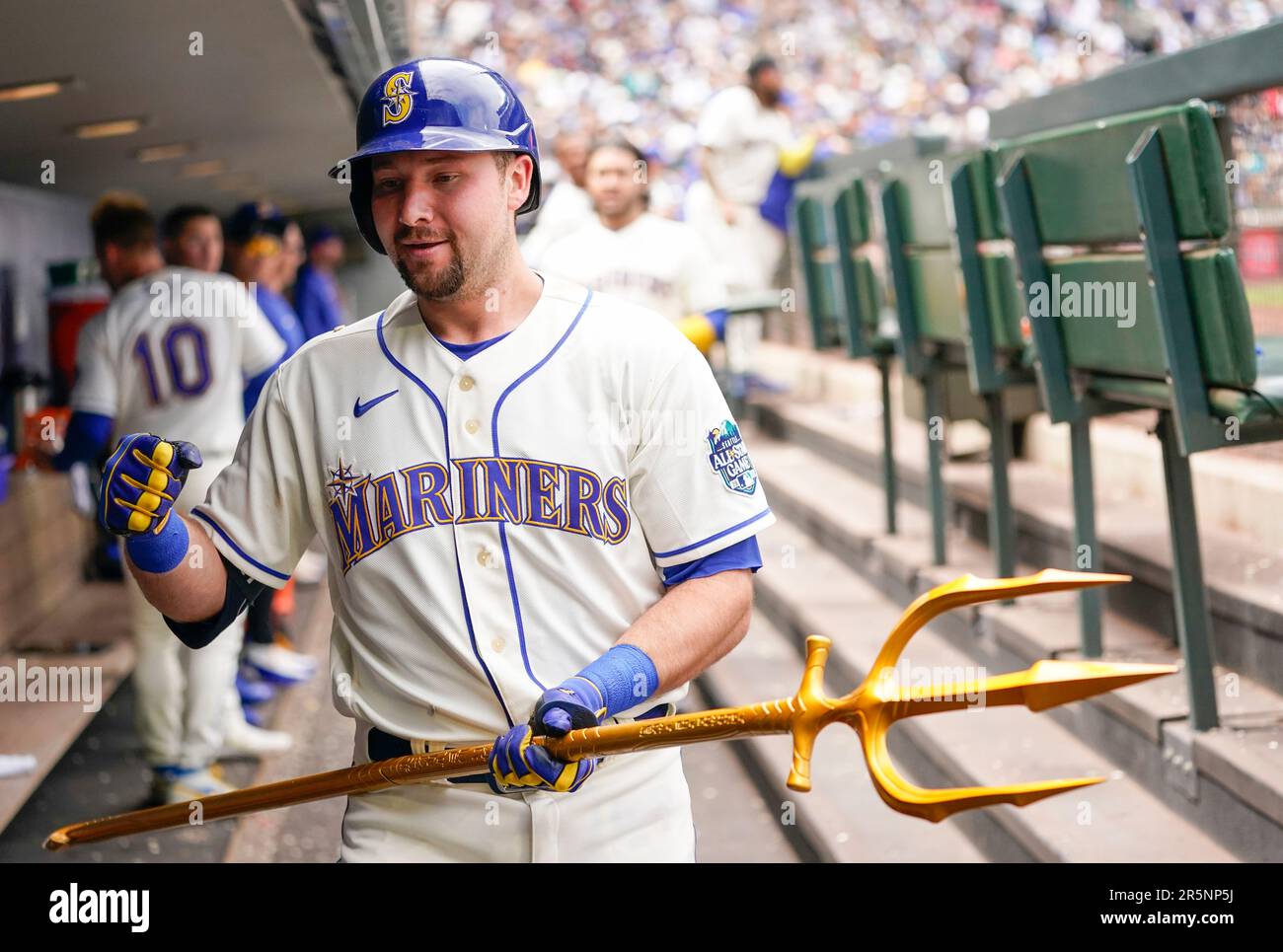Seattle Mariners' Cal Raleigh smiles while holding a trident in the