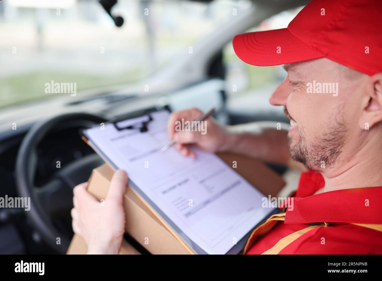 Courier driver fills in delivery receipts in car Stock Photo Alamy