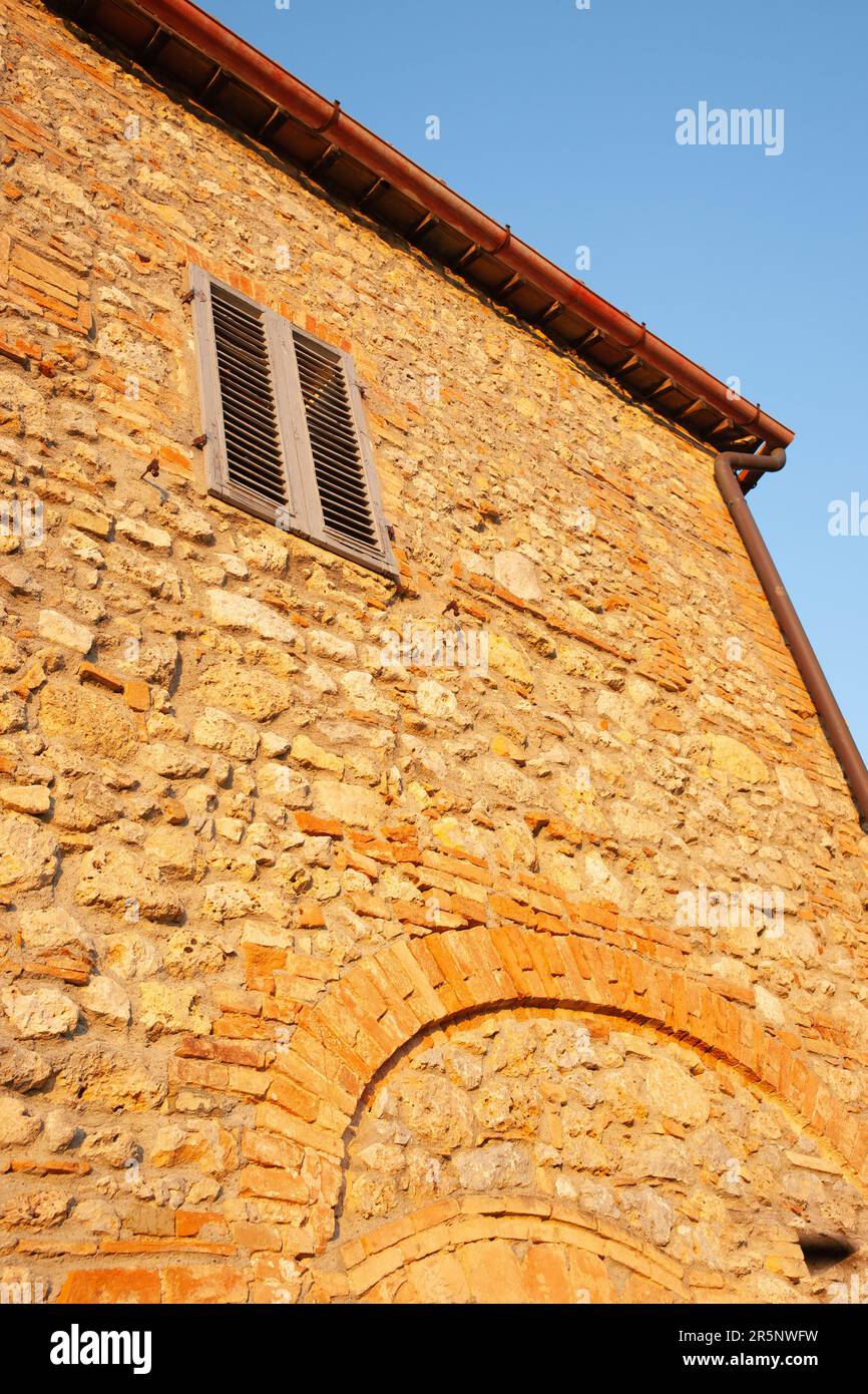 Shutter in stone wall in low point of view perspective under blue sky ...