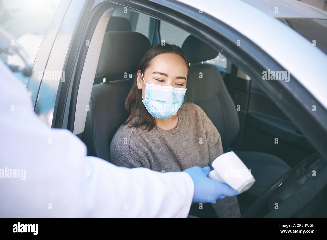 Stay alert, stay safe. a masked young woman getting her temperature ...