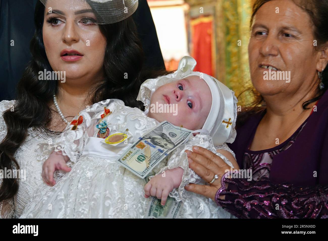 Diyarbakir, Turkey. 04th June, 2023. Mother Hulya Karadayi is seen with her baby, who is given dollars and gold by relatives after baptism, as a tradition. The baptism ceremony of the sons of Mushe Akbulut and Hulya Karadayi was held at the Syriac Ancient Church of the Virgin Mary of Diyarbak?r according to Syriac traditions. Because the number of Assyrians living in Diyarbakir has decayed so much, Mushe and Hulya became the first Assyrians to marry after a 40-year break. Credit: SOPA Images Limited/Alamy Live News Stock Photo