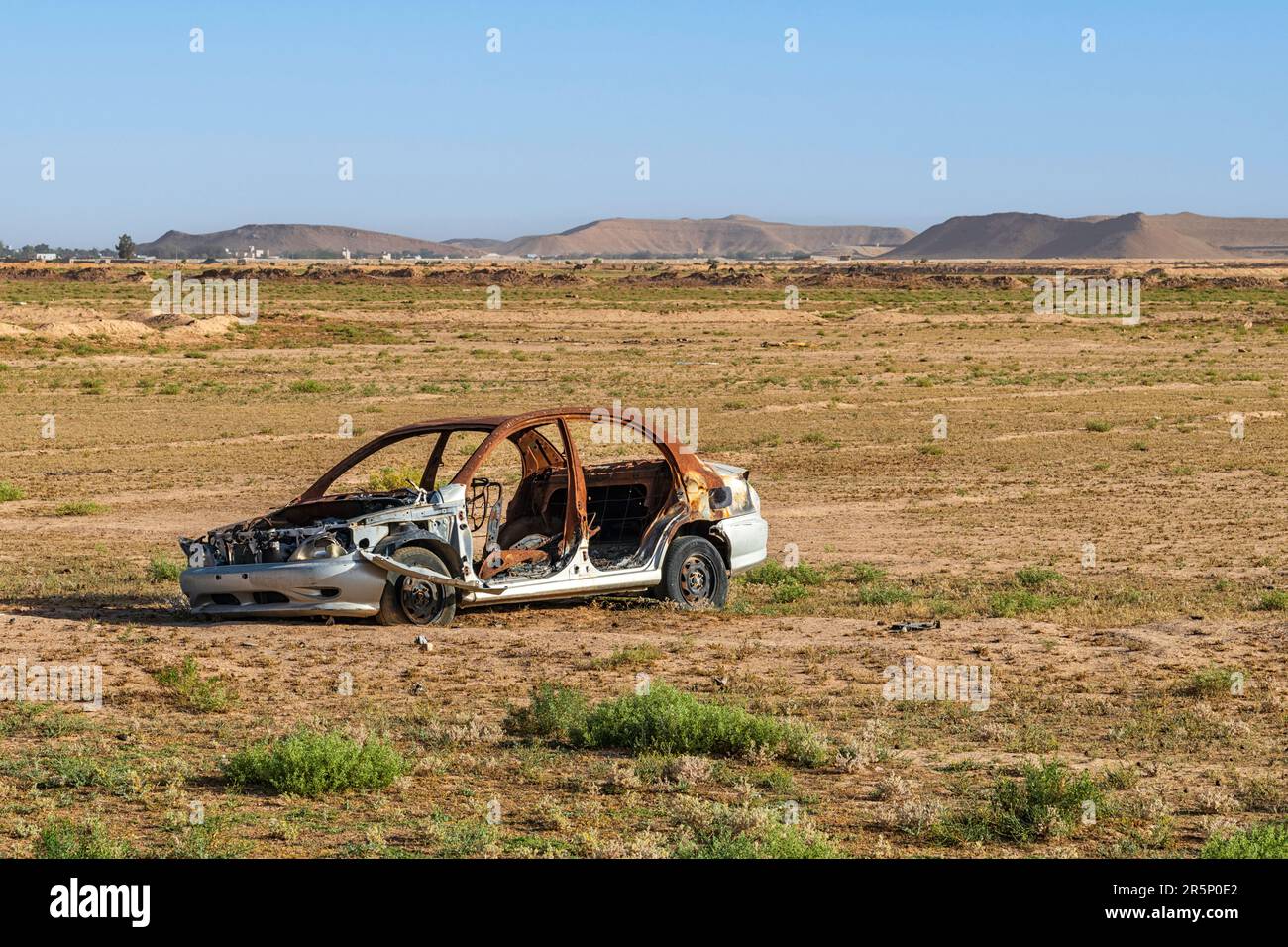 Burnt-out Car in Desert Stock Photo