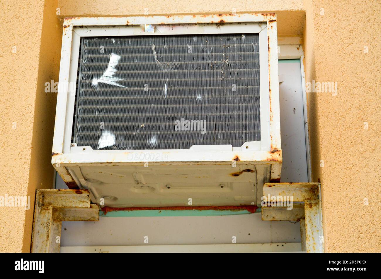 Old bad broken rectangular substandard rusty air conditioner for