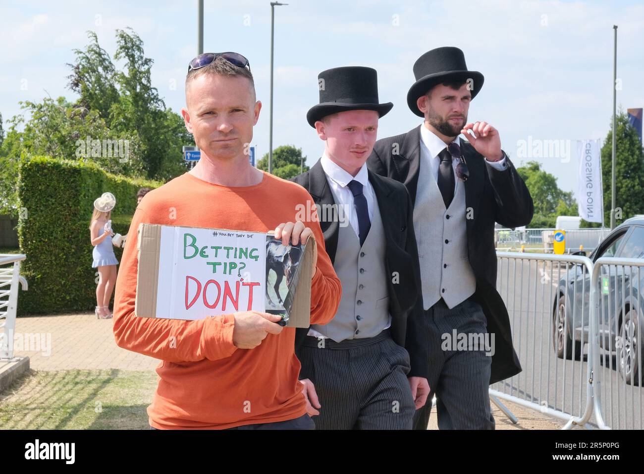 Epsom, UK. Racegoers pass an animal rights activist on Derby Day, highlighting the number of deaths of racehorses in 2022. Stock Photo