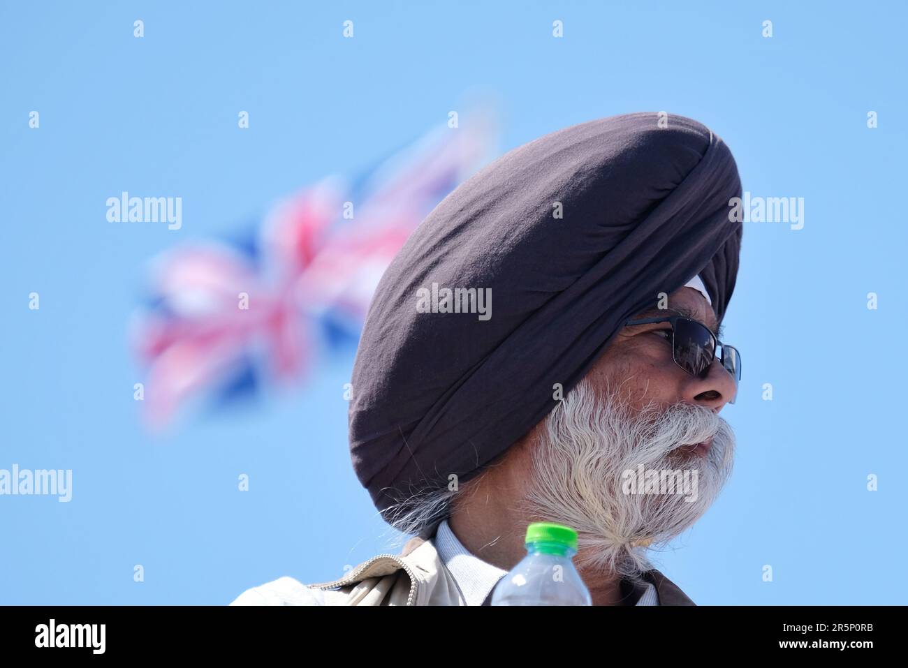 London, UK. A turbaned Sikh man with a Union flag seen flying in the background. Stock Photo