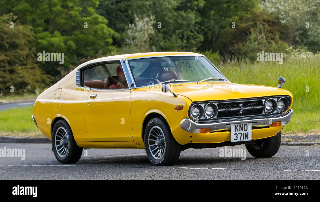 Stony Stratford,UK - June 4th 2023: 1975 yellow DATSUN 710 SSS  classic car travelling on an English country road. Stock Photo