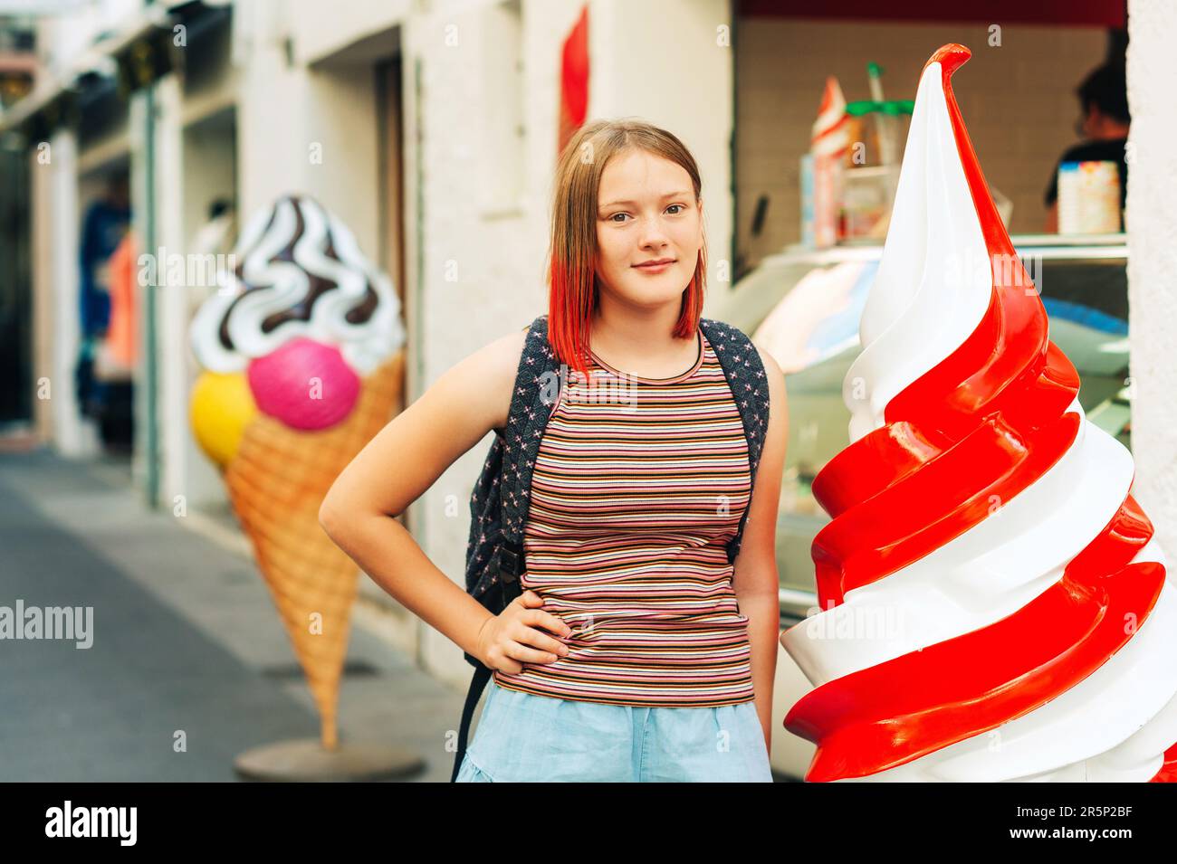 Outdoor portrait of pretty teenage girl with red dyed hair posing outside with giant ice cream Stock Photo