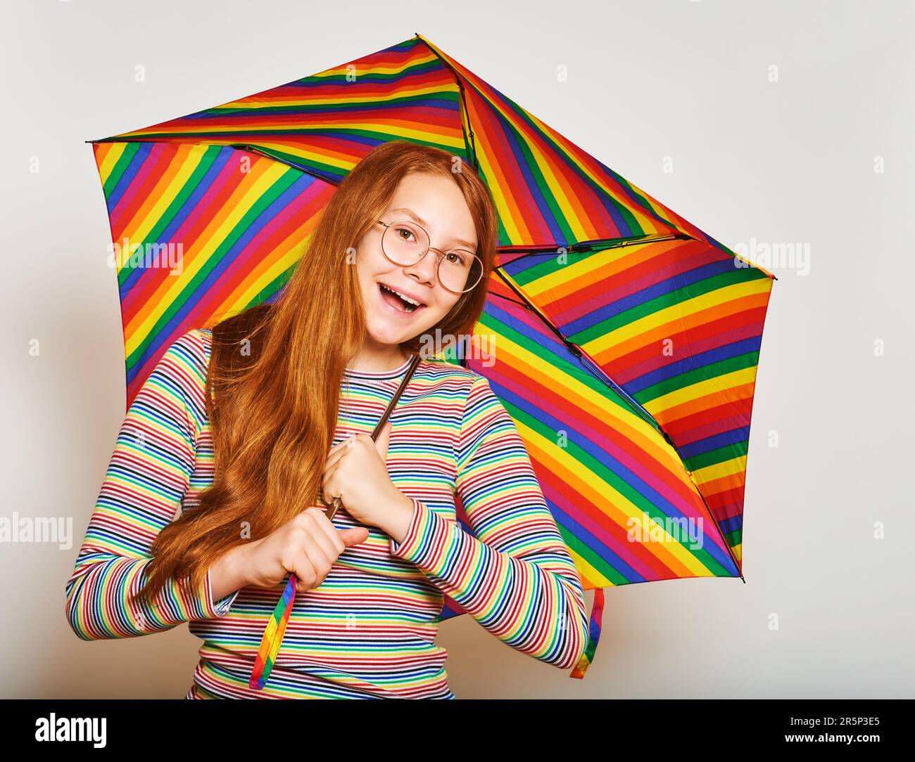 Studio portrait of young red-haired girl holding colorful umbrella Stock Photo