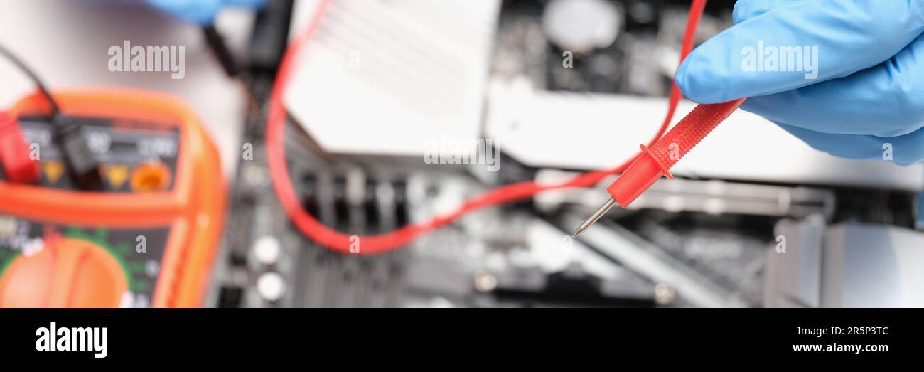 Technician using voltmeter to measure voltage on computer motherboard Stock Photo