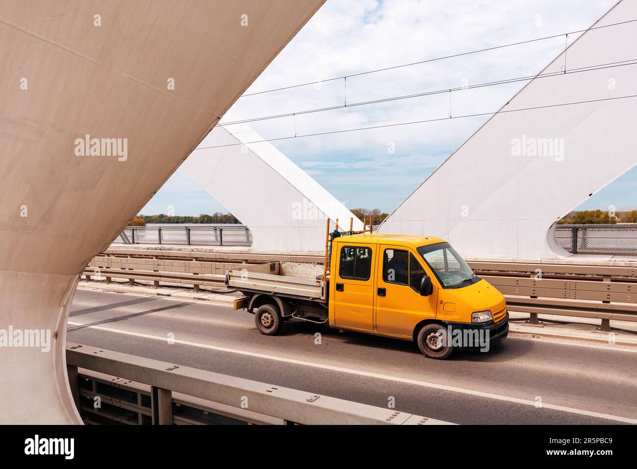 Yellow mini truck speeding over modern bridge, used in intra-city low tonnage cargo delivery,n Selective focus. Stock Photo