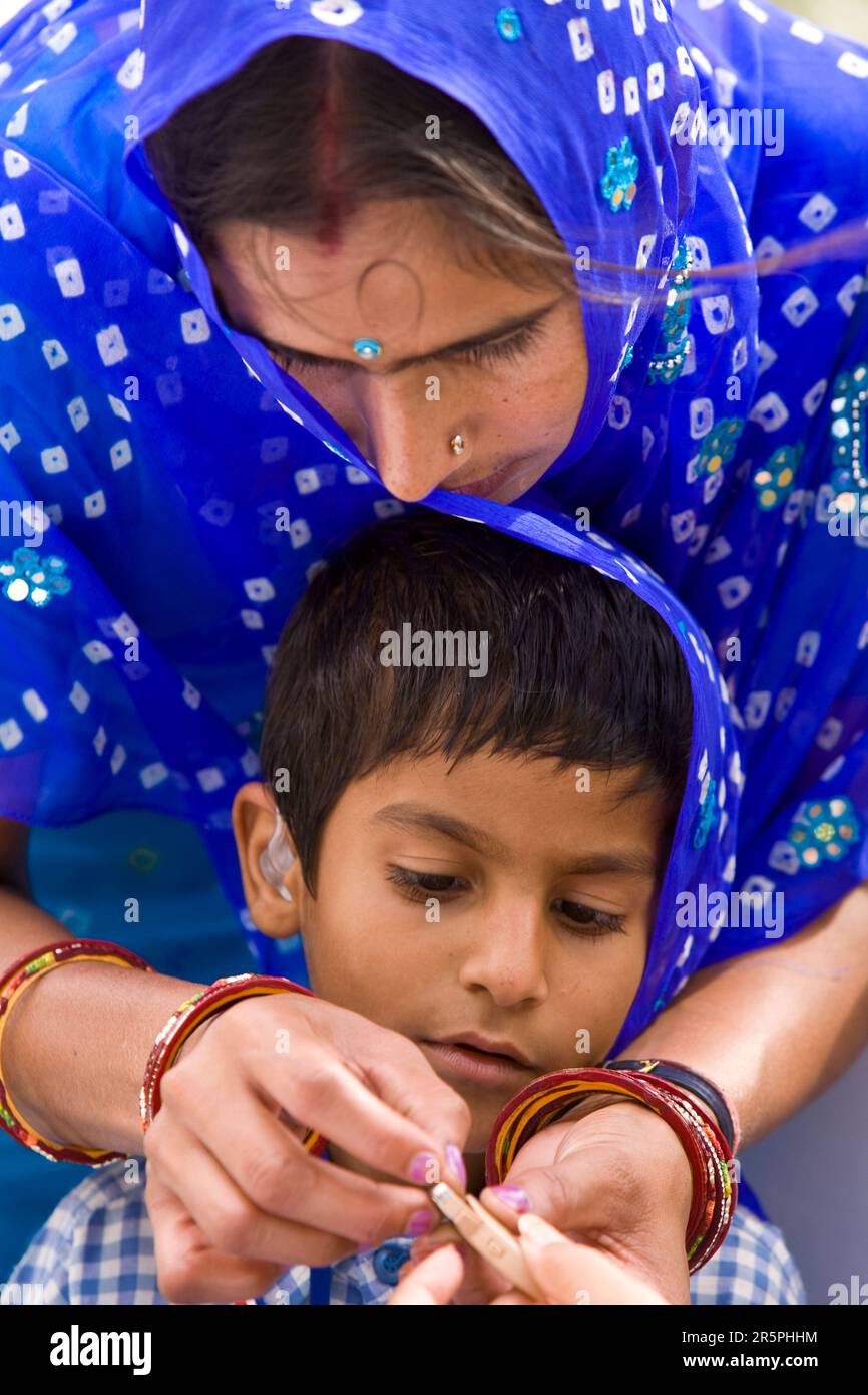 A mother shows her son how to install the batteries in his new hearing