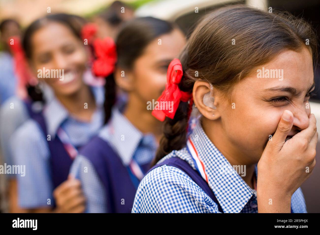 school girls laugh as they line up for the bus to return to school with a new sense of hearing and hope for the future. Stock Photo