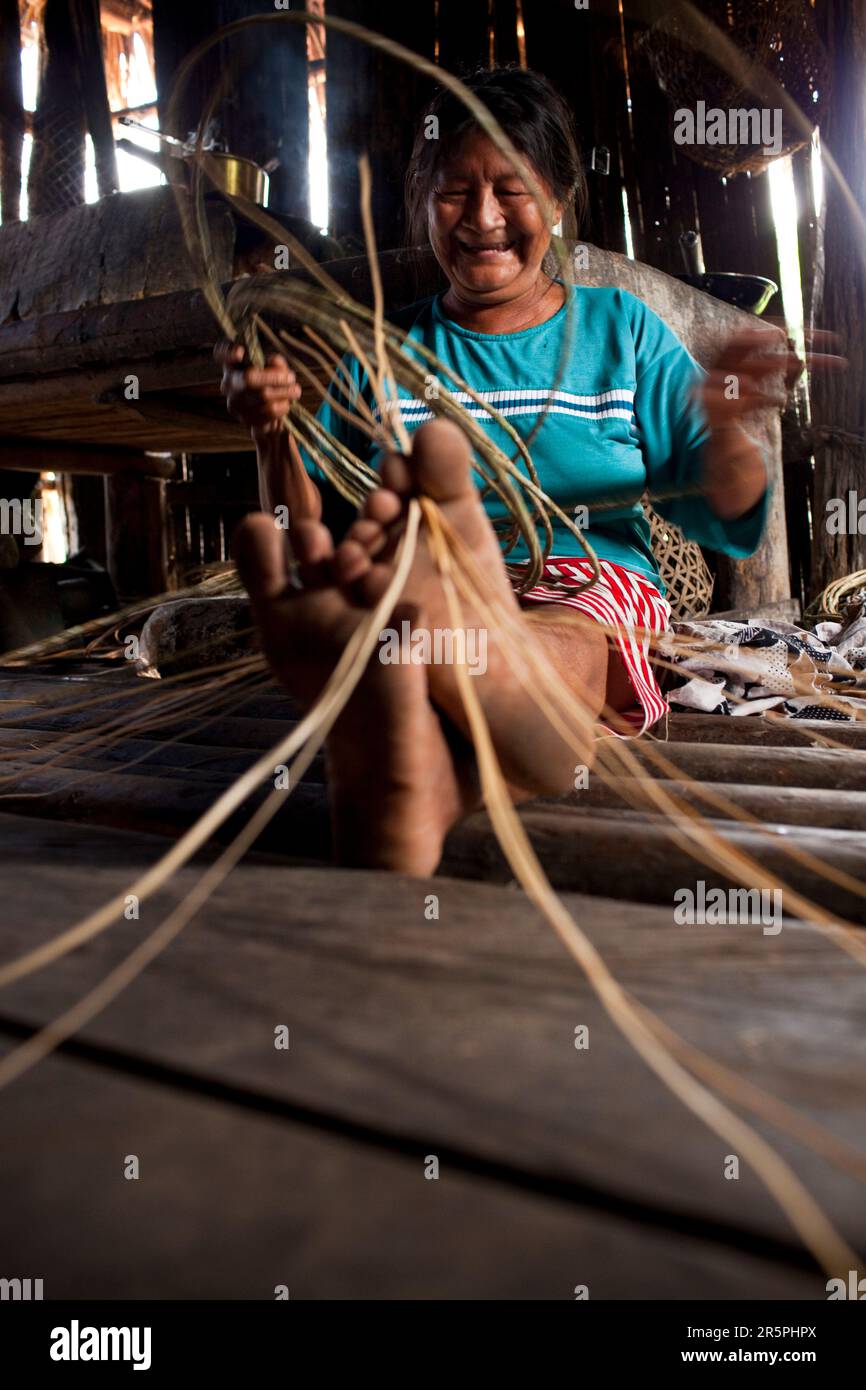 One of the elder Oro Win women enjoys weaving a basket of forest vines