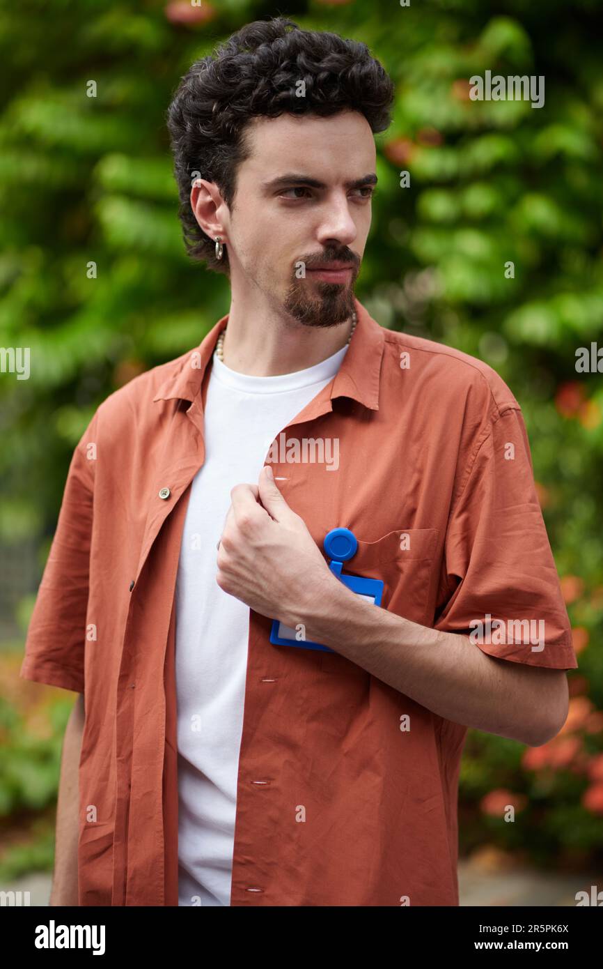 Portrait of developer with curly hair standing outdoors and looking away Stock Photo