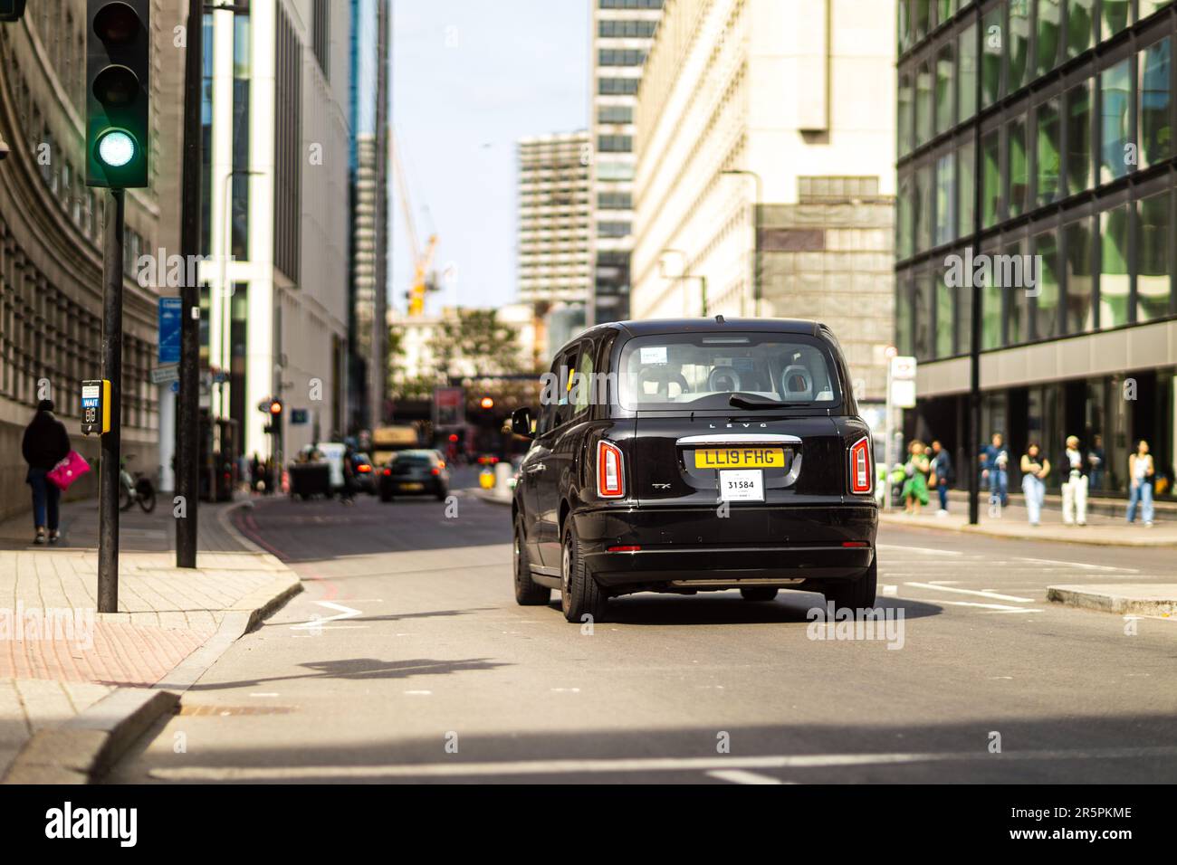 London, 29th May 2023: A modern electric cab is driving beside Forum Magnum Square. Stock Photo