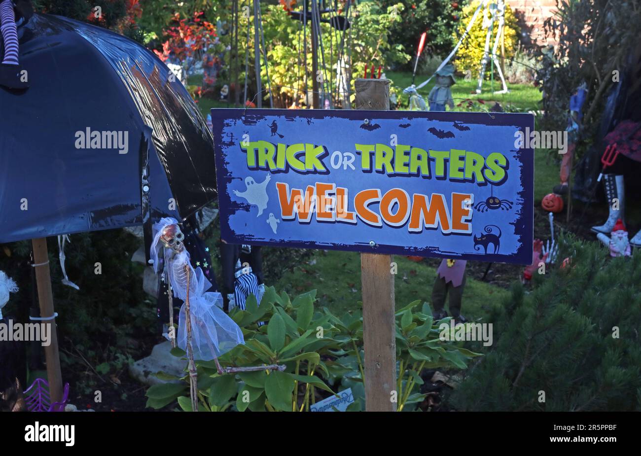 Trick or Treaters Welcome” sign displayed in a decorated garden during Halloween celebrations, encouraging children to take part in trick or treating Stock Photo