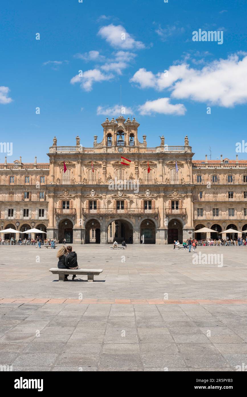 Holiday couple, rear view in summer of a young couple looking at the grand town hall sited in the baroque Plaza Mayor in the city of Salamanca, Spain Stock Photo
