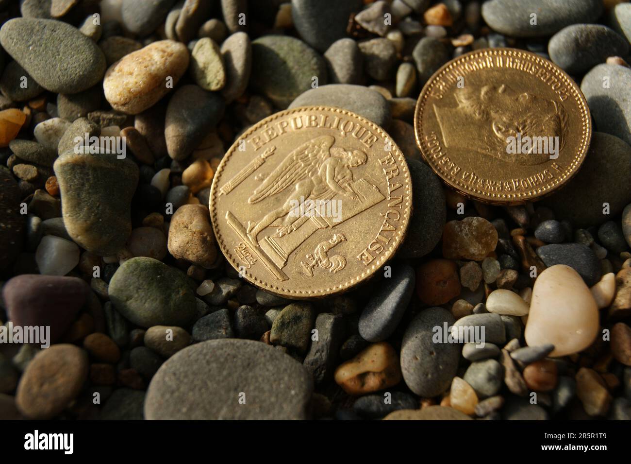Russian and French old gold coins on stones. Stock Photo