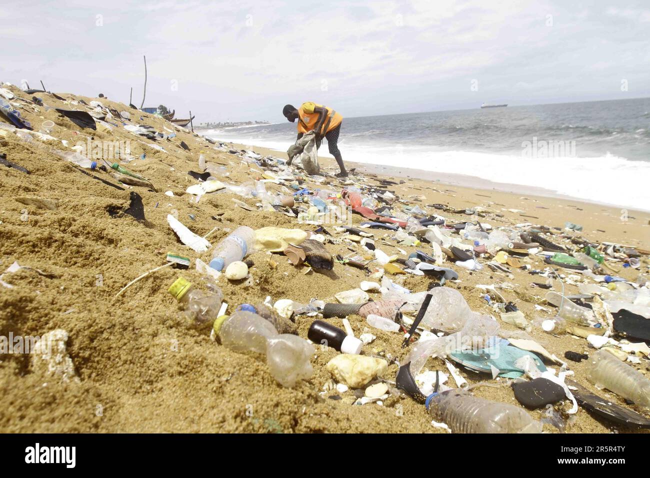 a-trash-collector-picks-up-plastic-along-port-bouet-beach-outside