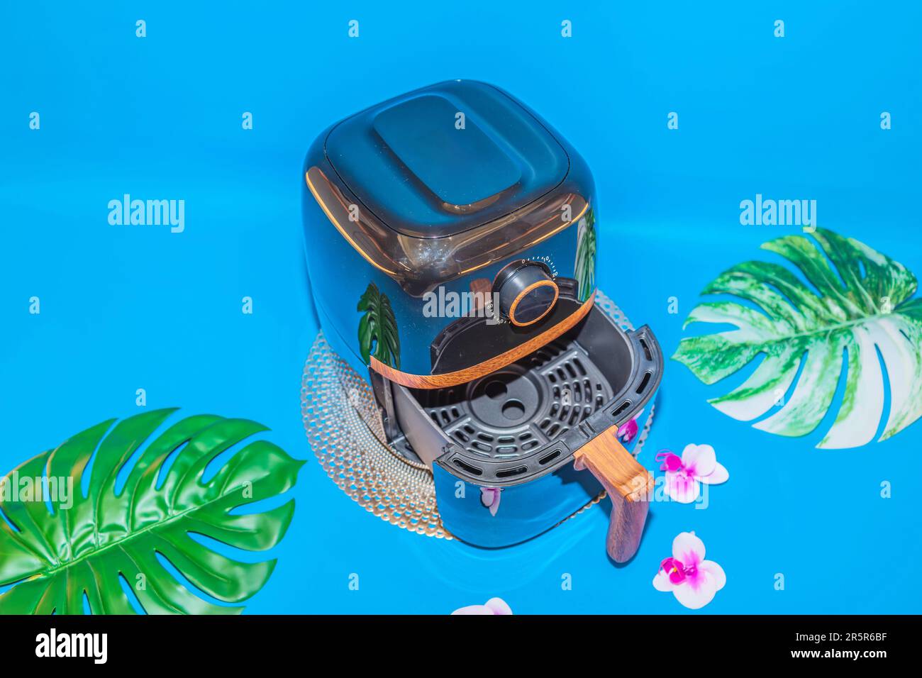 The Black Air Fryer with Wooden Handle Design offers a combination of sleek aesthetics and practical functionality. Stock Photo