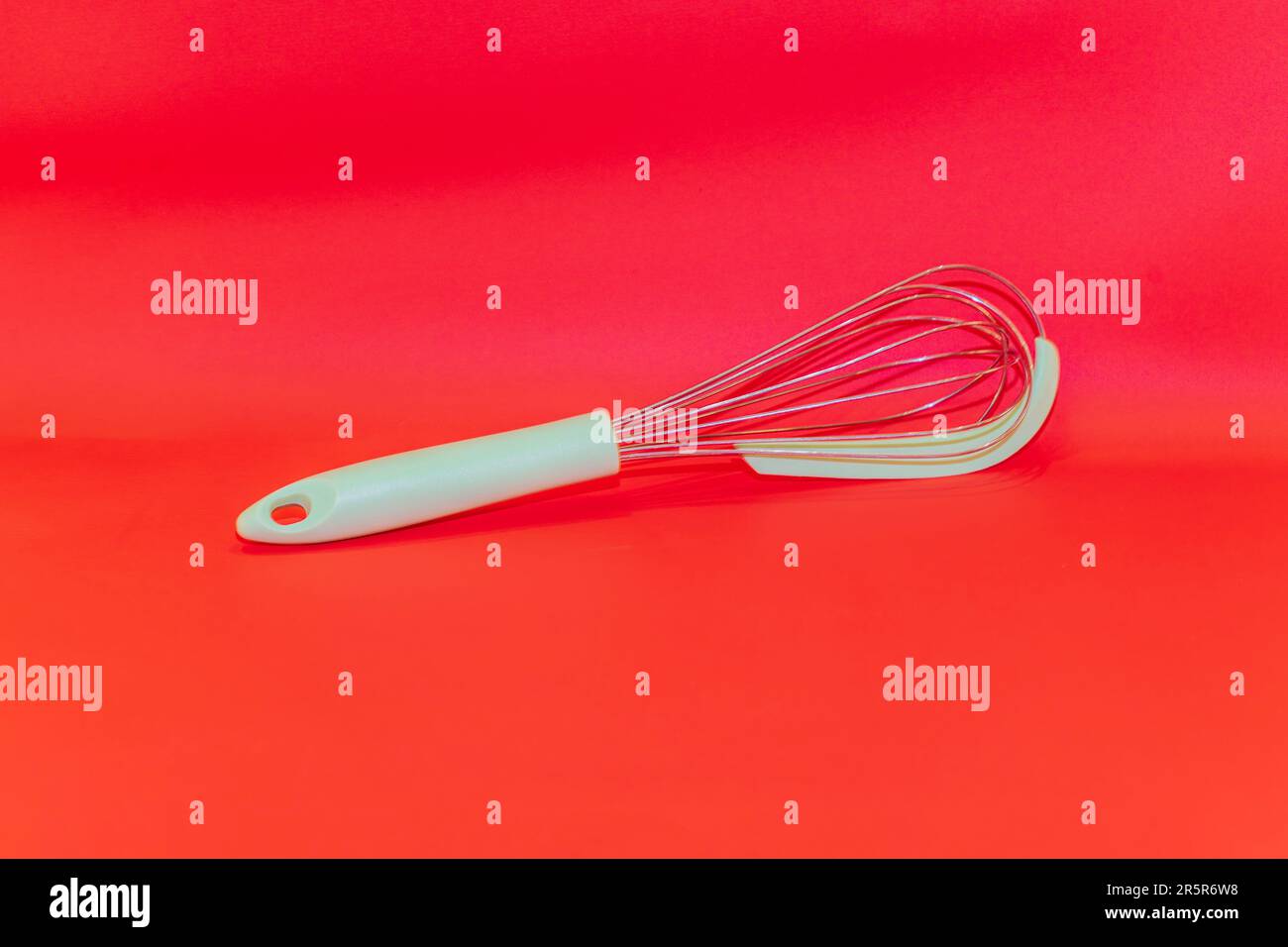 The Green-Handled Manual Egg Beater is a versatile kitchen tool that makes whisking and beating eggs a breeze. Stock Photo