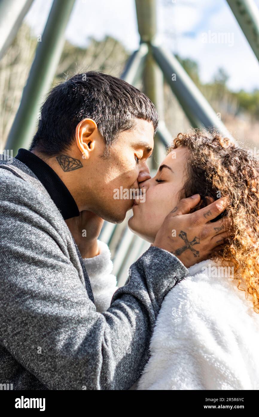 An affectionate young couple in a loving embrace, standing beneath an ...