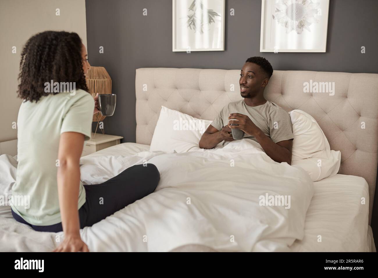 Smiling young multiracial couple talking over coffee in bed Stock Photo ...
