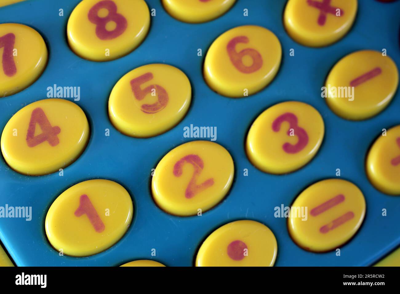 A close up photo of the yellow number keys on a retro toy cash register. Stock Photo